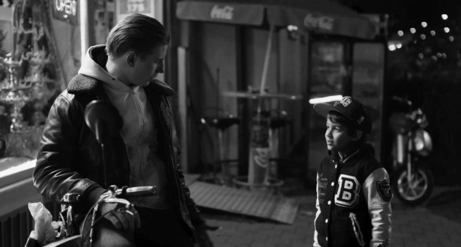 Filmstill aus dem Film "The Kids Are Alright" zeigt einen jungen Mann mit Motorrad, der mit einem kleinen Jungen spricht.